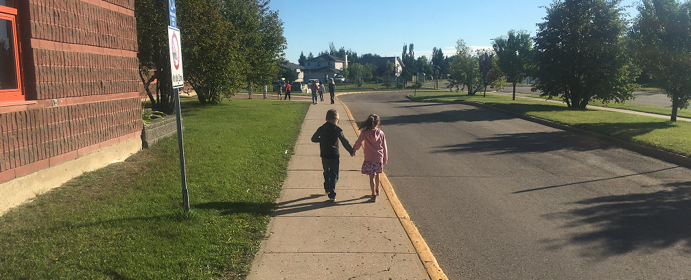 Young boy and girl holding hands walking away from camera