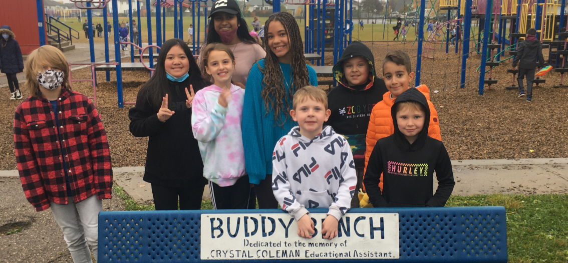 Ethnically diverse group of children standing behind a buddy bench